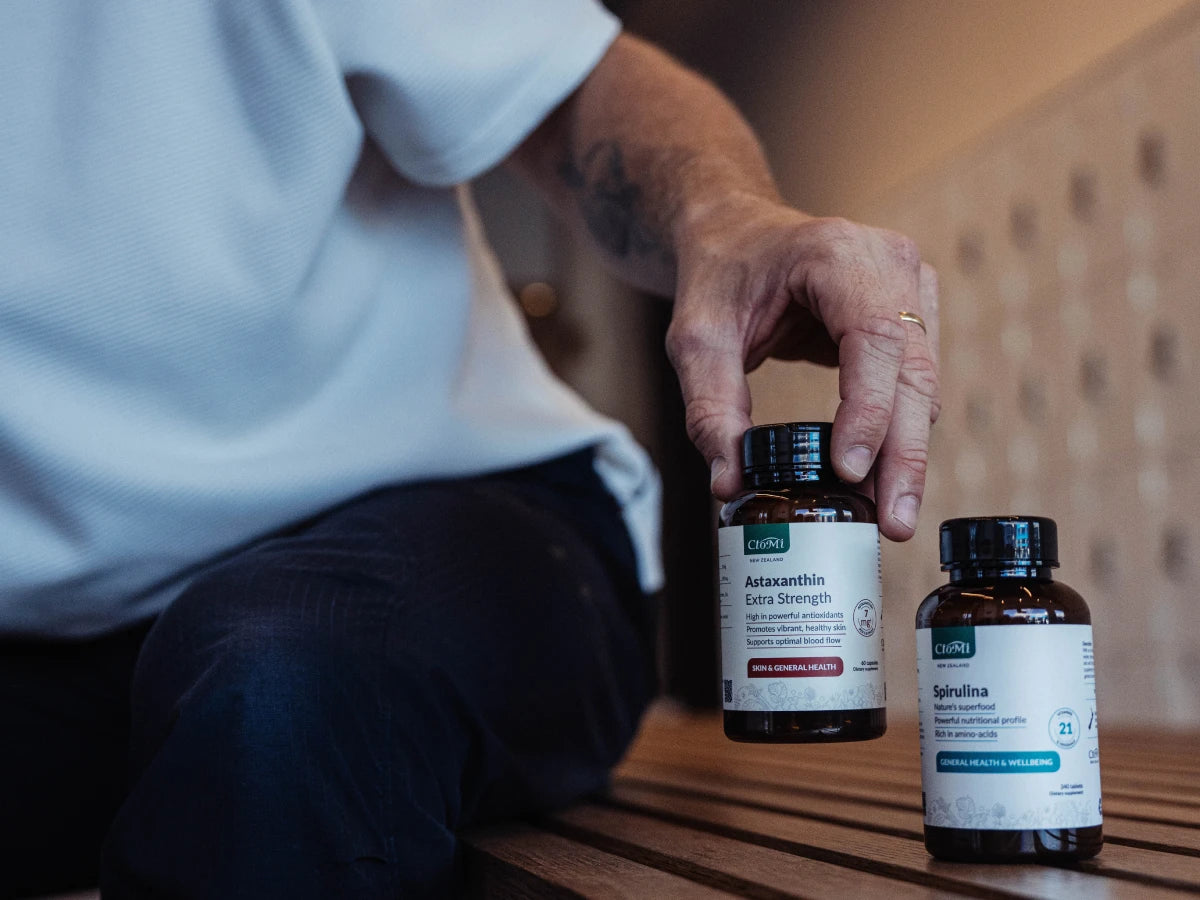Lifestyle shot of a person holding a CtoMi Astaxanthin and Spirulina daily energy supplement bottle
